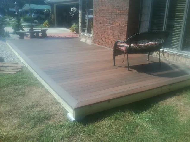 New wood deck and wicker chair beside a brick house in Montrose