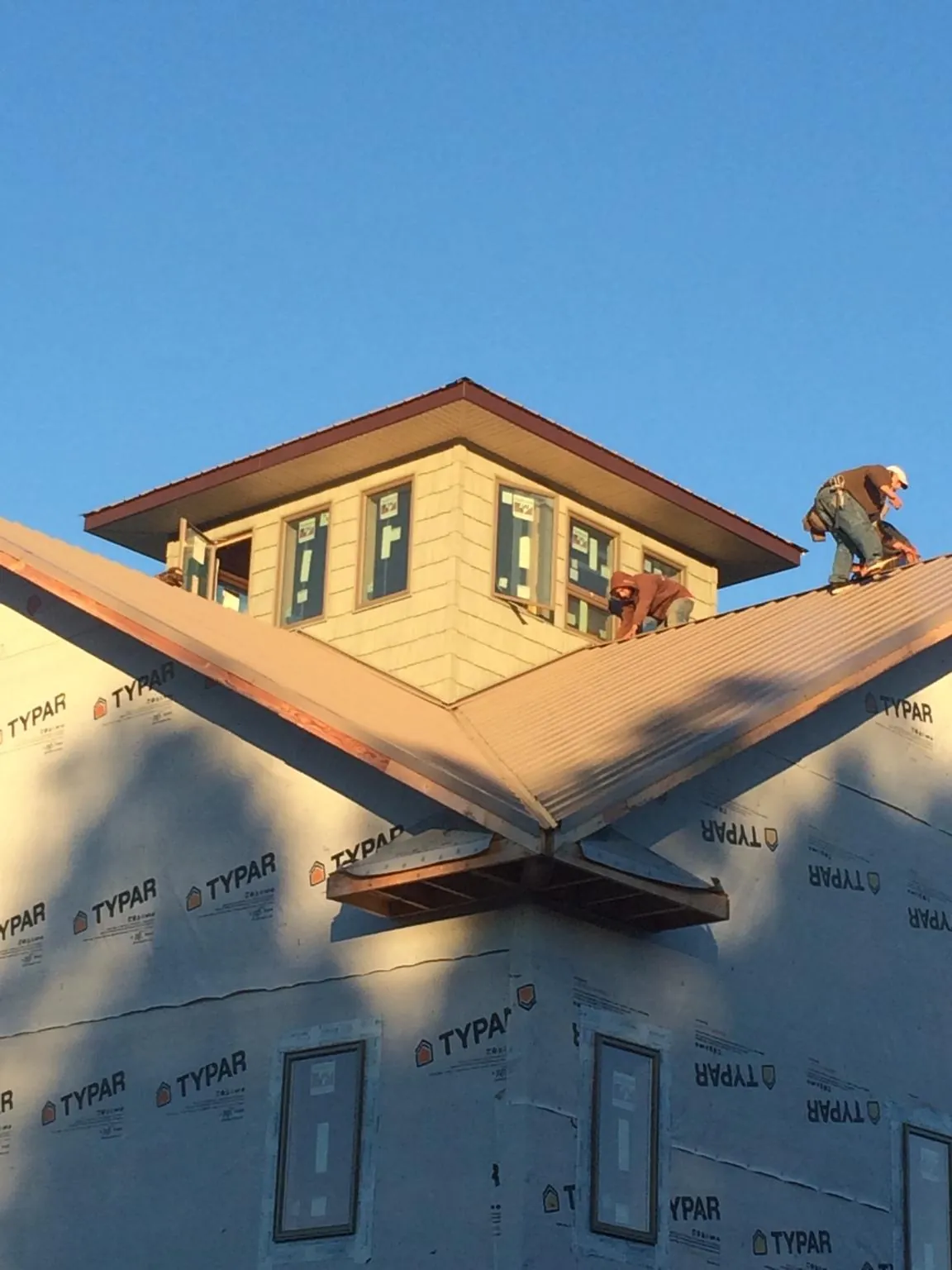 Roofers working around a rooftop cupola on a new metal roof at sunset — Roof Waterproofing in Montrose by Roofing Brothers